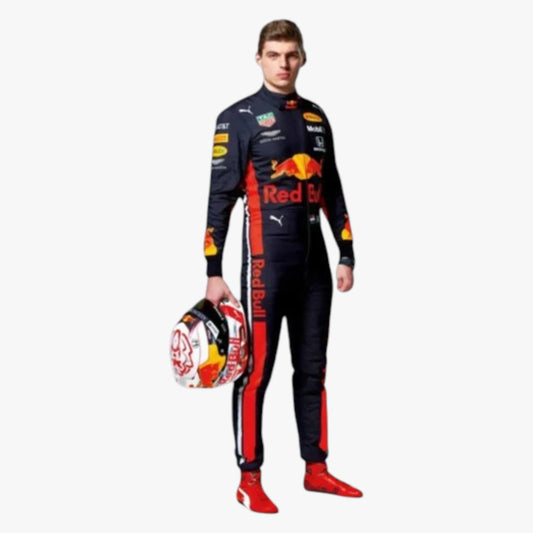 A man wearing a full Red Bull racing suit and helmet, standing against a plain light gray background. The suit is predominantly black with red and yellow graphics and sponsor logos, and he is holding a white, red, and black racing helmet.