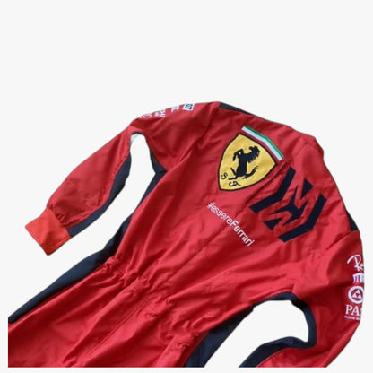 A red long-sleeve Scuderia Ferrari racing suit with navy blue side panels and logos, laid flat on a light gray background.