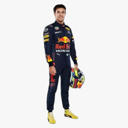 A man wearing a dark navy Red Bull Racing team suit with sponsor logos, holding a colorful racing helmet, standing against a plain light gray background.