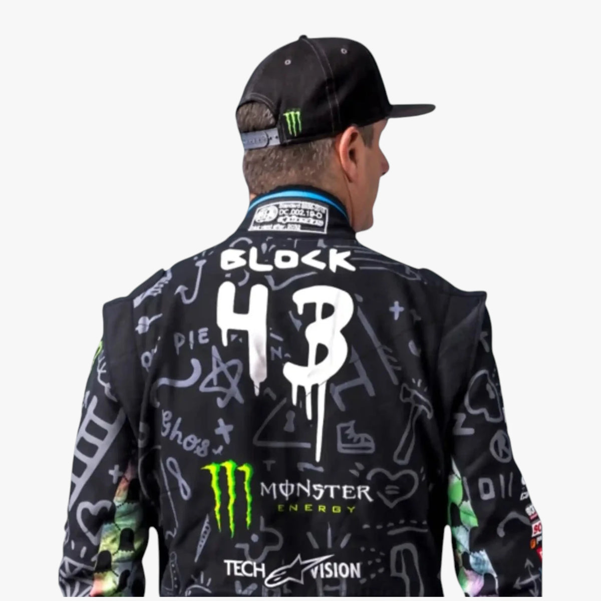Racing jacket with a black base and white graffiti-style graphics, featuring 'BLOCK 43' on the back, a green Monster Energy logo, and a black cap with a green Monster logo, shown on a model from the back against a light gray background.