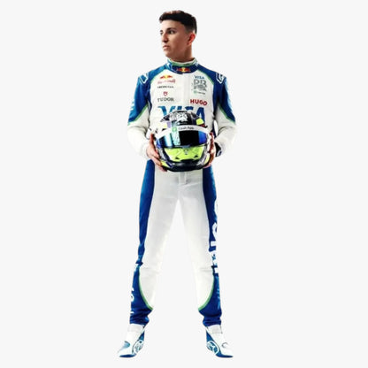 A full-body shot of a male race driver wearing a blue and white Red Bull Racing suit, holding a matching helmet with a colorful graphic design, set against a plain white background.