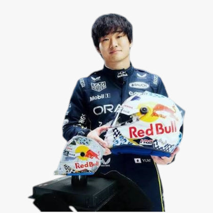 A man in a Red Bull racing suit holds two Red Bull racing helmets, one large and one smaller, against a plain white background.
