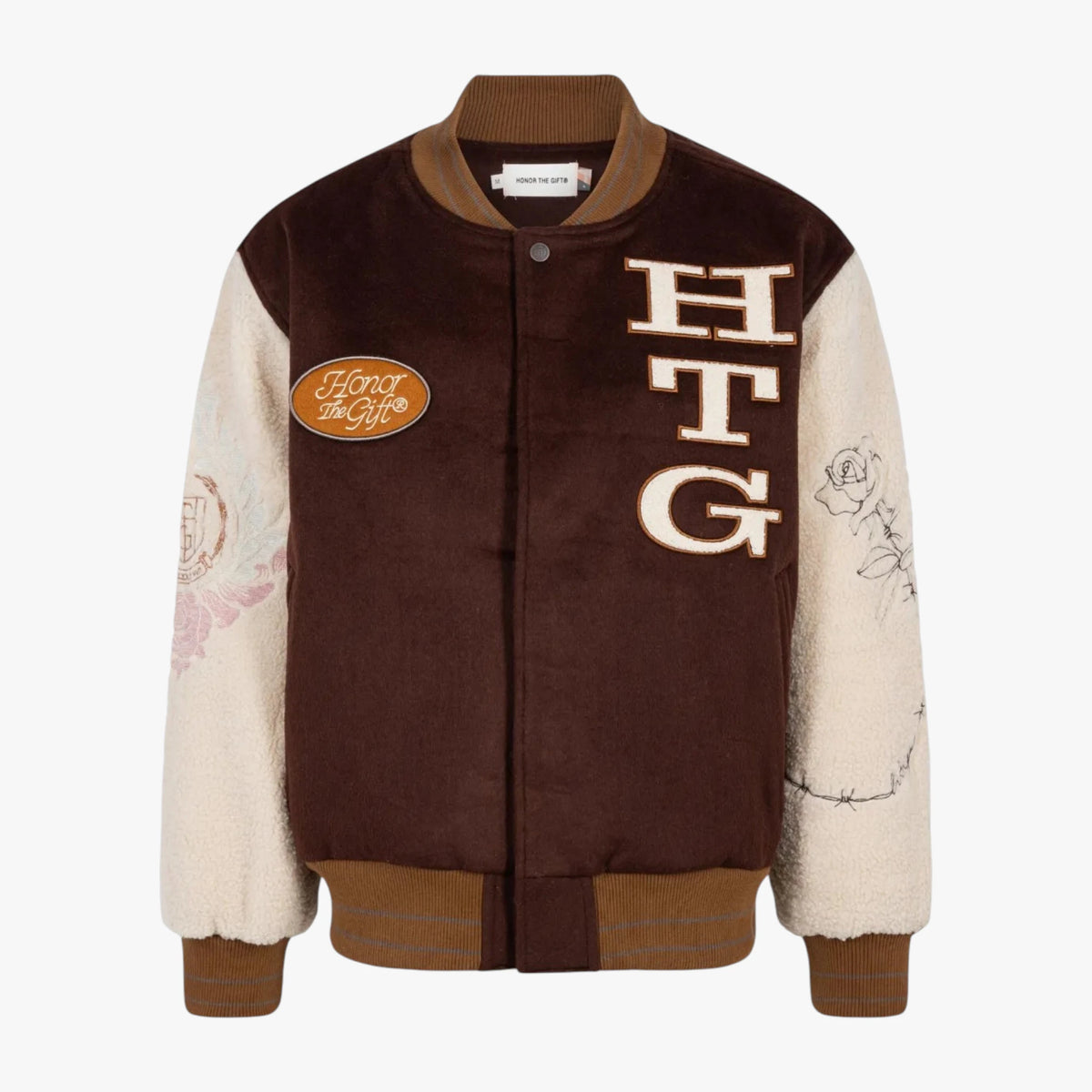 A brown and cream varsity-style jacket with 'HTG' lettering on the chest, a circular 'Hot Topic' patch on the left chest, and floral line art on the right sleeve, shown against a light gray background.