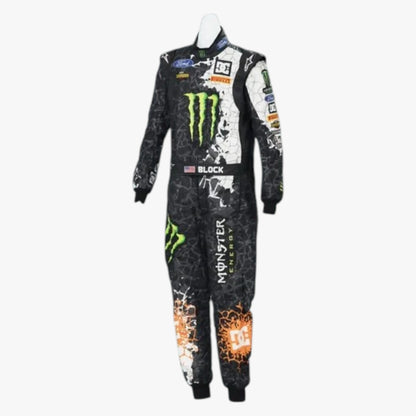 A full-length racing one-piece suit displayed on a mannequin against a light gray background. The suit is primarily black with a white splatter graphic, featuring prominent green Monster Energy logos, an orange DC logo near the lower leg, and sponsor patches including Ford and Alpinestars.