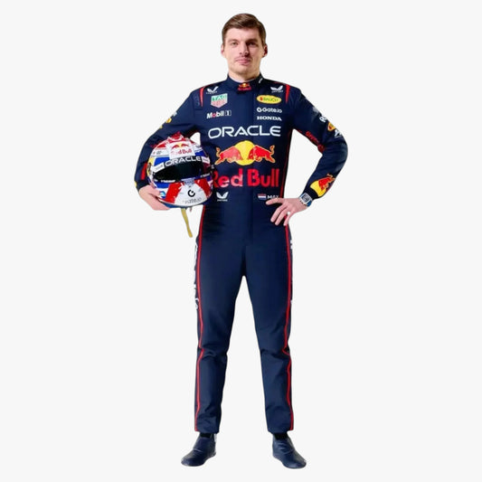 A man stands against a light gray background wearing a dark navy Red Bull Racing team suit with multiple sponsor logos, holding a red, white, and blue racing helmet.